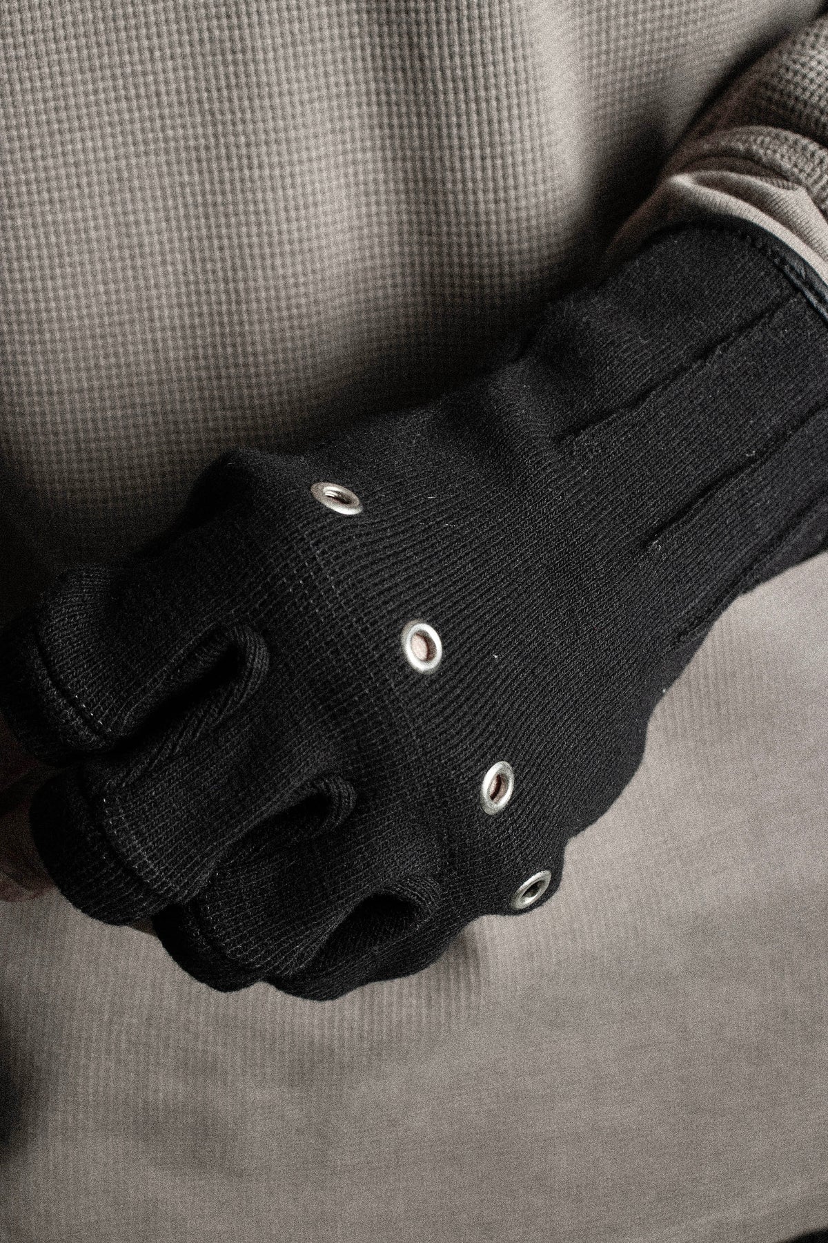 Close-up of metal knuckle eyelets on the black cotton rib Ākhira glove